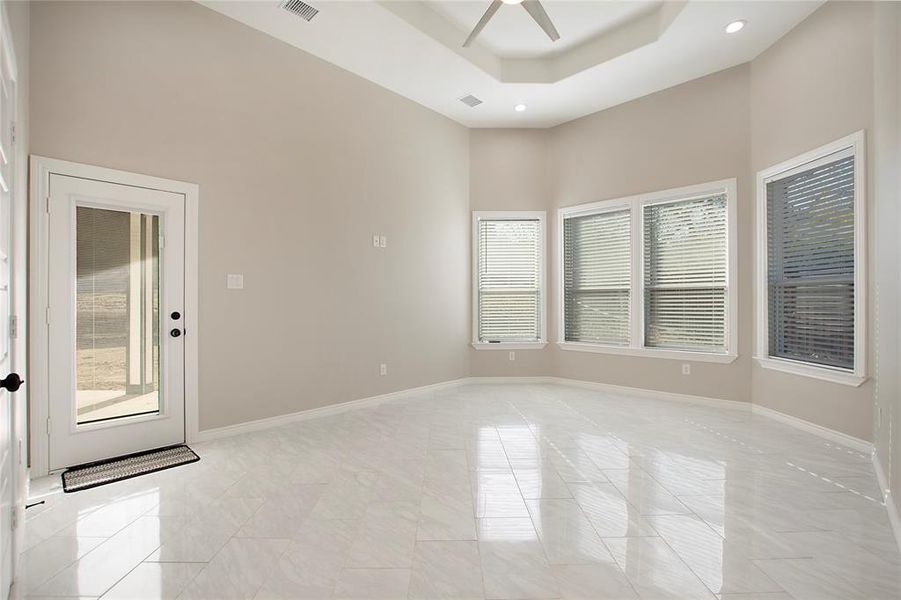 Spare room with ceiling fan, a towering ceiling, and a tray ceiling