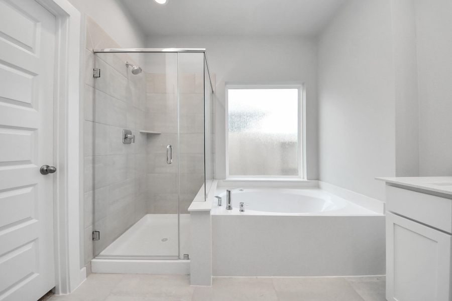 Indulge in a spa-like retreat within the confines of this primary bathroom. Delight in a spacious walk-in shower enveloped in stylish tile surround, unwind in a separate garden tub adorned with custom detailing.