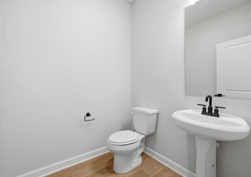 Half bathroom featuring a pedestal sink and toilet on the first floor.