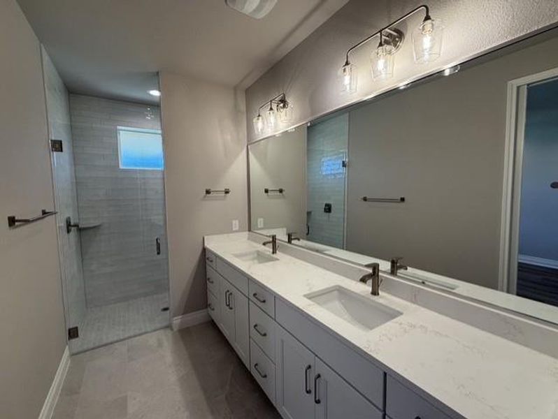 Dual vanity with pristine countertops complements a spacious walk-in shower. Dual vanity with pristine countertops complements a spacious walk-in shower.
