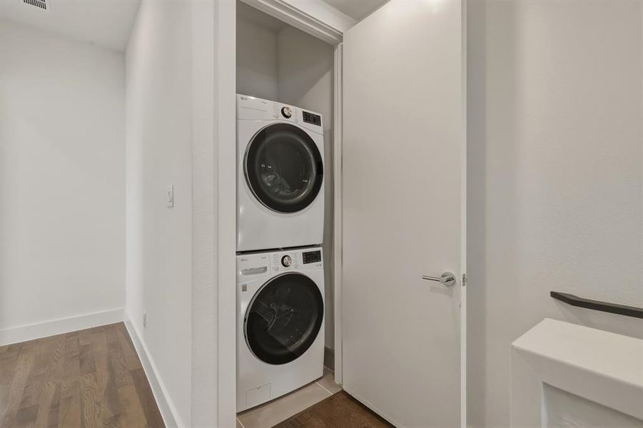 Laundry area with stacked washer / drying machine and dark wood-style flooring