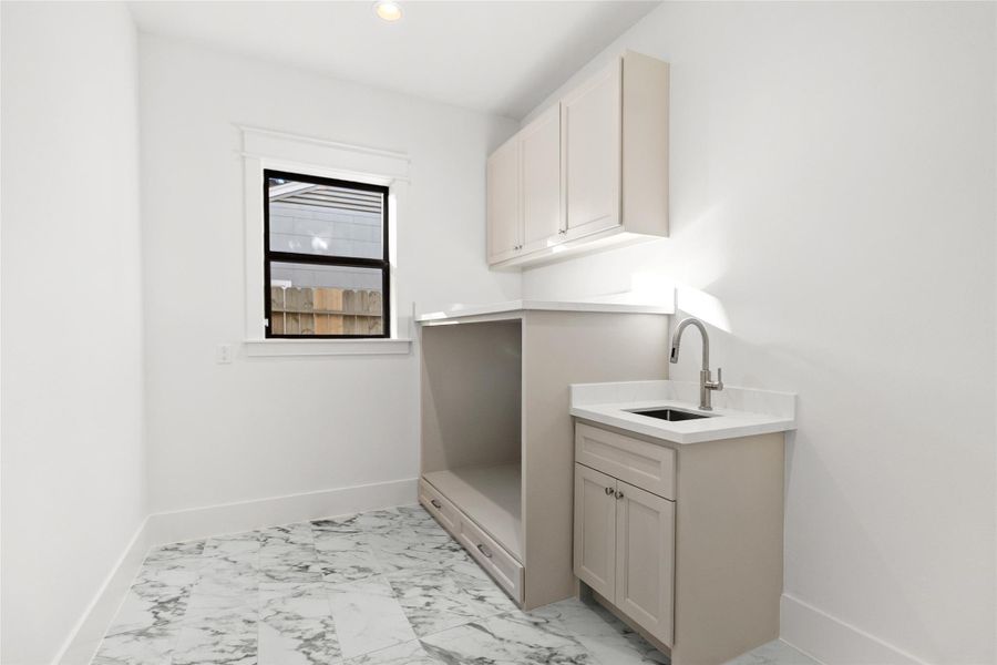 Laundry day feels effortless in this bright, thoughtfully designed space. You’ve got custom cabinetry for storage, a deep utility sink for handwashing or cleanups, and generous counter space that makes folding and organizing feel simple instead of rushed.