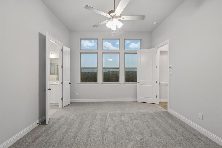 Unfurnished bedroom featuring light colored carpet, ensuite bathroom, and a ceiling fan Unfurnished bedroom featuring light colored carpet, ensuite bathroom, and a ceiling fan