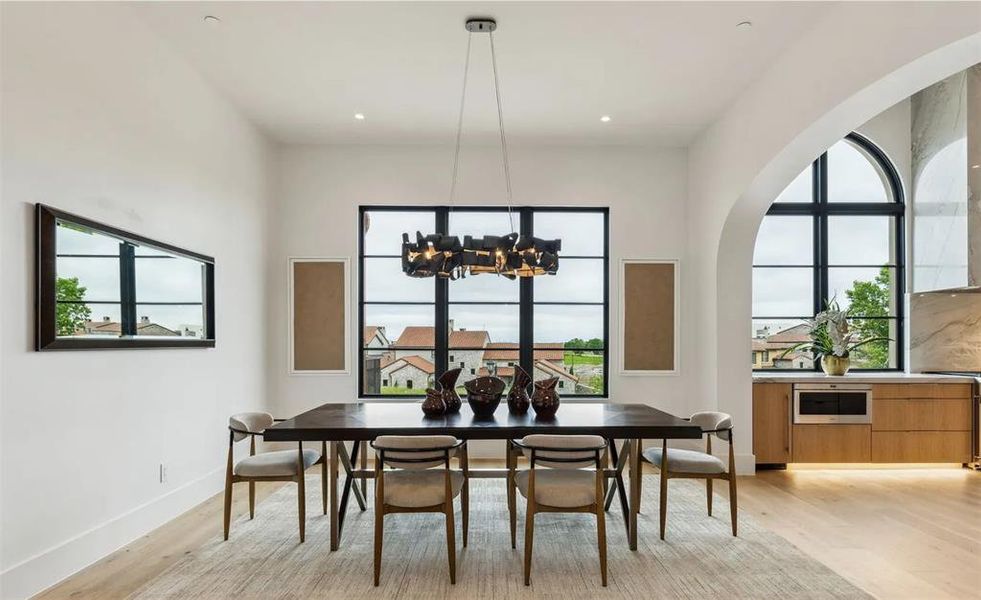 Dining space with light wood-style flooring, arched walkways, recessed lighting, and a chandelier