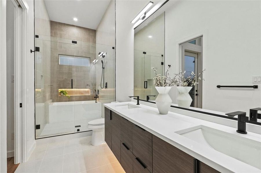 Bathroom featuring vanity, toilet, tile patterned floors, and a shower with shower door