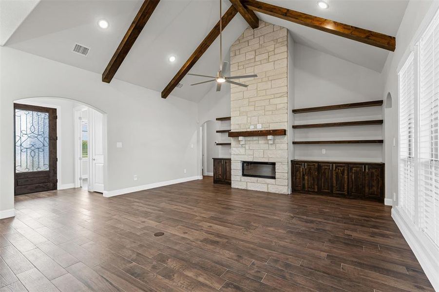 Unfurnished living room with arched walkways, high vaulted ceiling, a fireplace, beam ceiling, and recessed lighting Unfurnished living room with arched walkways, high vaulted ceiling, a fireplace, beam ceiling, and recessed lighting
