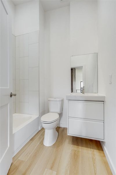 Full bathroom featuring vanity, light wood finished floors, and shower / bath combination Full bathroom featuring vanity, light wood finished floors, and shower / bath combination