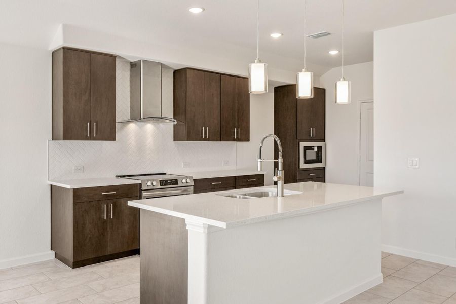 Kitchen with dark wood cabinets, white quartz island, stainless steel appliances, and pendant lights