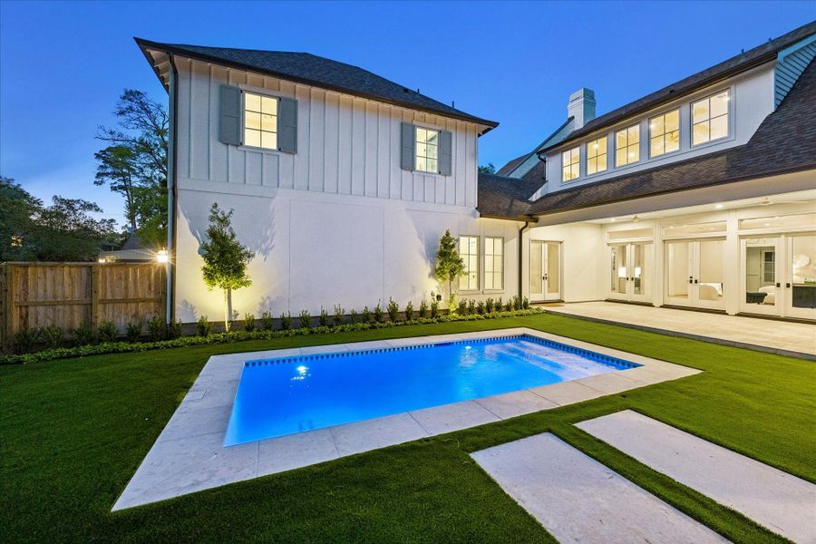 This perspective highlights the designated covered relaxation areas surrounding the pool, offering flexible space for seating. The turf extends throughout the backyard while lighted trees create a natural backdrop & soft evening lighting to bring the outdoors in!