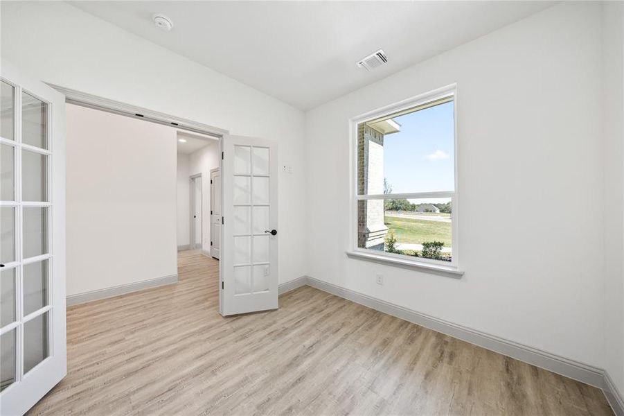 Unfurnished room with french doors, light wood-type flooring, and vaulted ceiling
