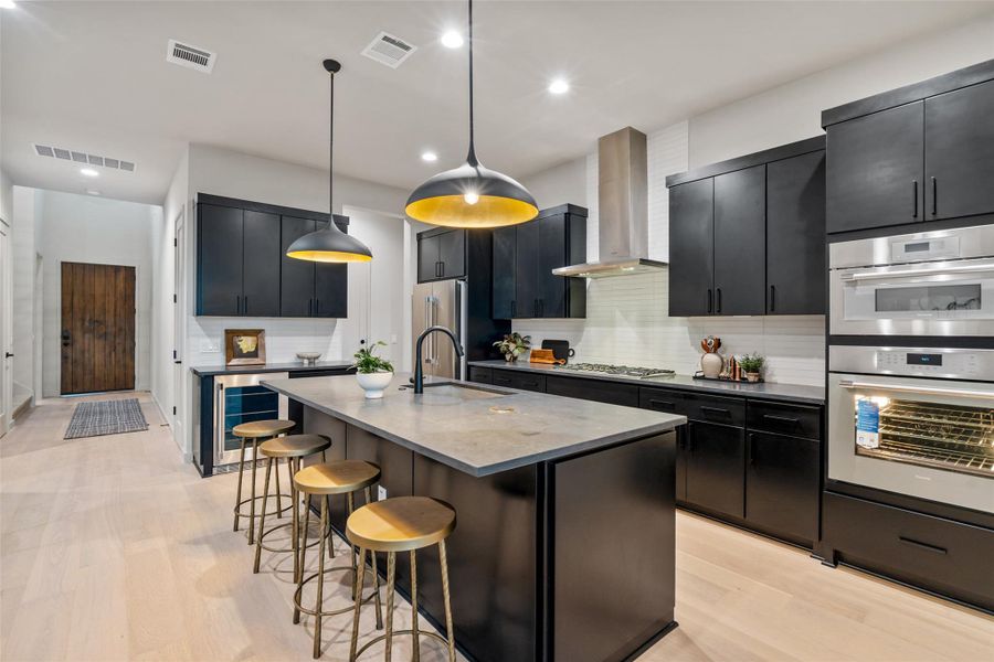 A contemporary chef's kitchen boasts a central island, elegant dark cabinetry, and premium stainless steel appliances. A contemporary chef's kitchen boasts a central island, elegant dark cabinetry, and premium stainless steel appliances.