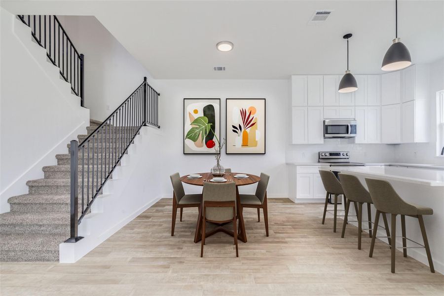A vibrant open-concept layout features a well-lit kitchen and a modern staircase. A vibrant open-concept layout features a well-lit kitchen and a modern staircase.