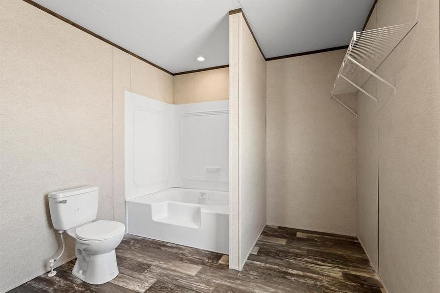 Bathroom with dark wood-style flooring, crown molding, and recessed lighting