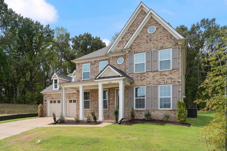Brick exterior with grey shutters, covered front porch, and a two-car garage Brick exterior with grey shutters, covered front porch, and a two-car garage
