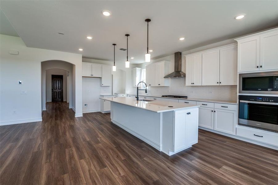 Kitchen featuring white cabinetry, stainless steel appliances, and wall chimney exhaust hood