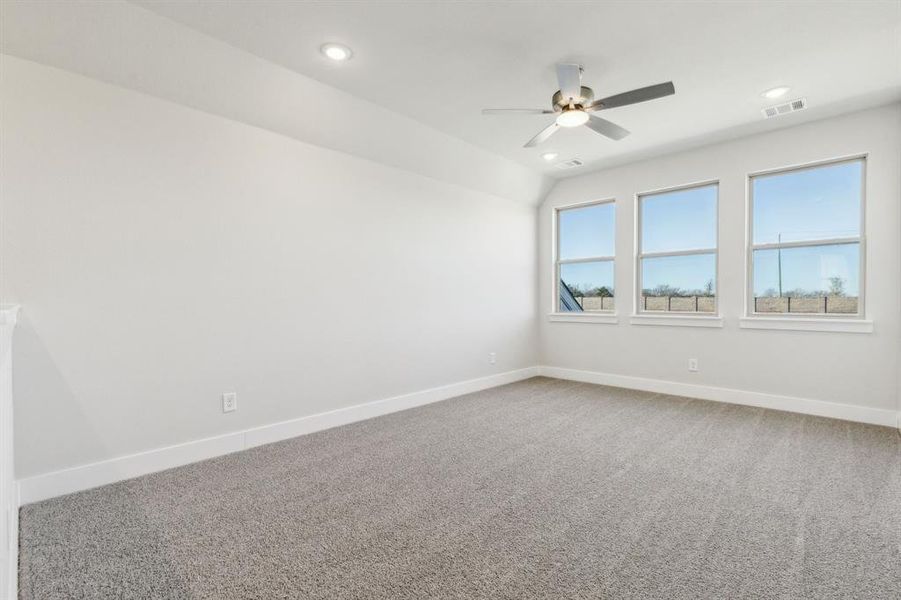 Carpeted empty room featuring lofted ceiling and ceiling fan