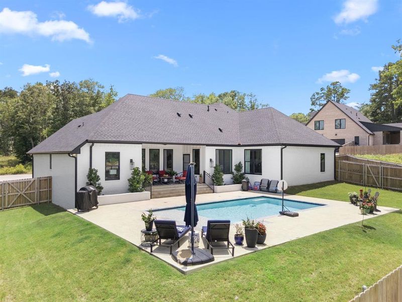 Back of house featuring a patio area, a fenced backyard, roof with shingles, and stucco siding Back of house featuring a patio area, a fenced backyard, roof with shingles, and stucco siding