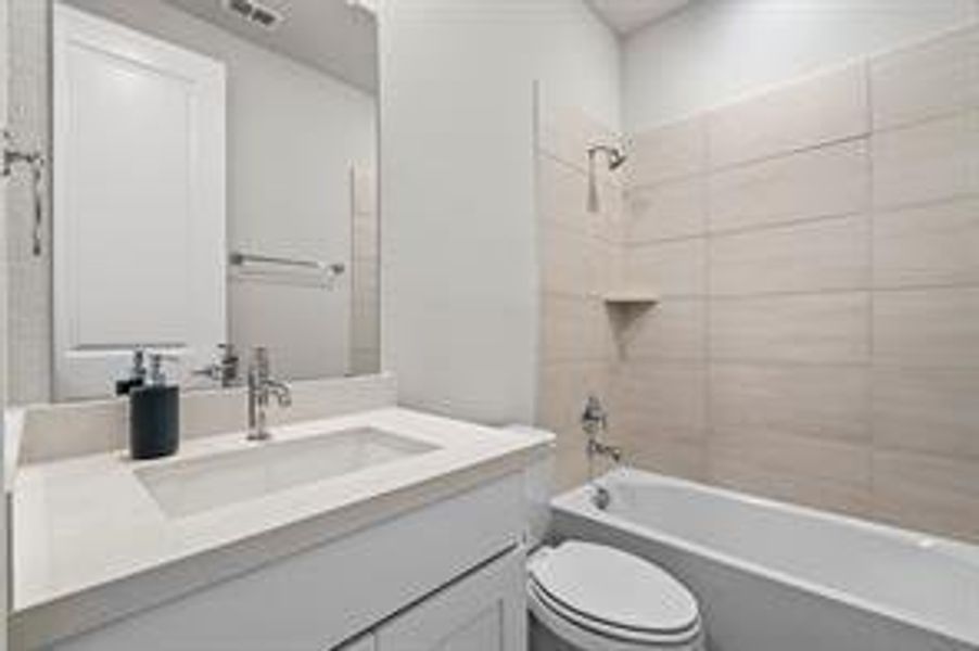 Full bathroom featuring vanity, toilet, and tiled shower / bath combo