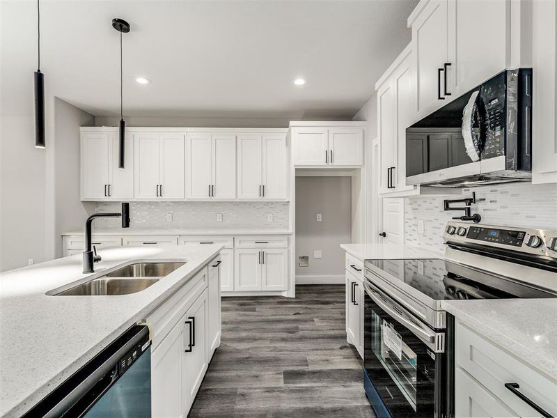 Kitchen featuring pendant lighting, white cabinets, sink, light stone countertops, and appliances with stainless steel finishes