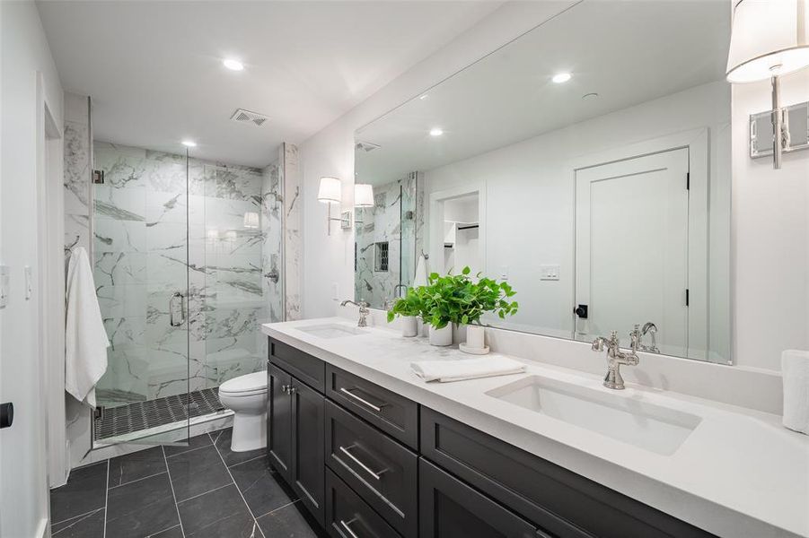 Bathroom with tile patterned floors, vanity, toilet, and a shower with door