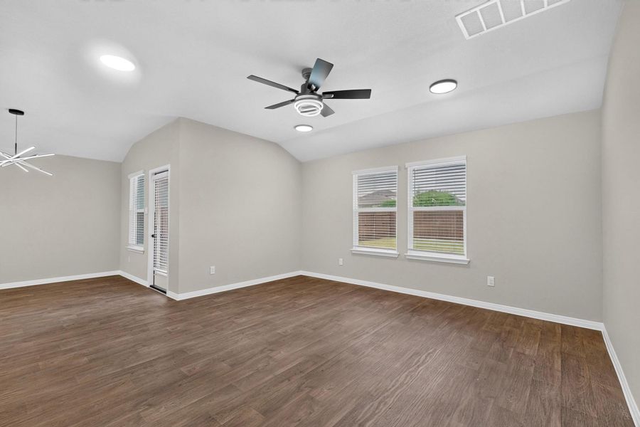 Rich wood-look flooring and an airy vaulted ceiling define this versatile living space.