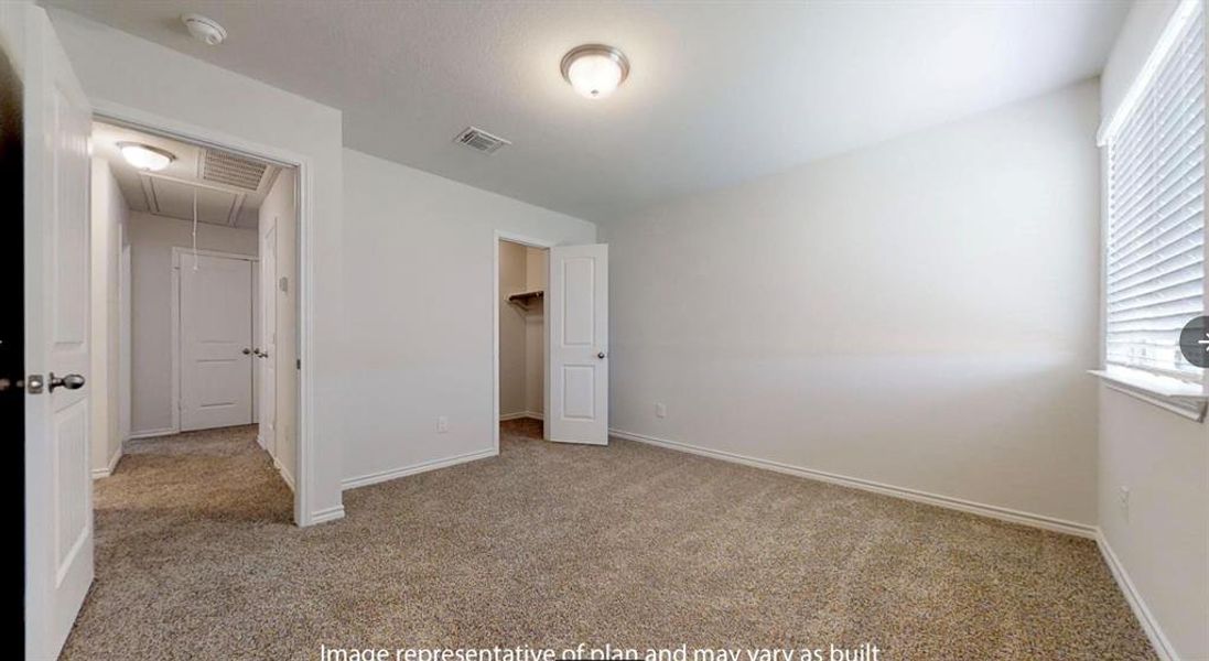 Unfurnished bedroom with attic access, carpet flooring, baseboards, and a walk in closet