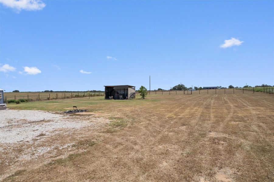 Fenced pastures and a functional outbuilding spread across the wide open country landscape.