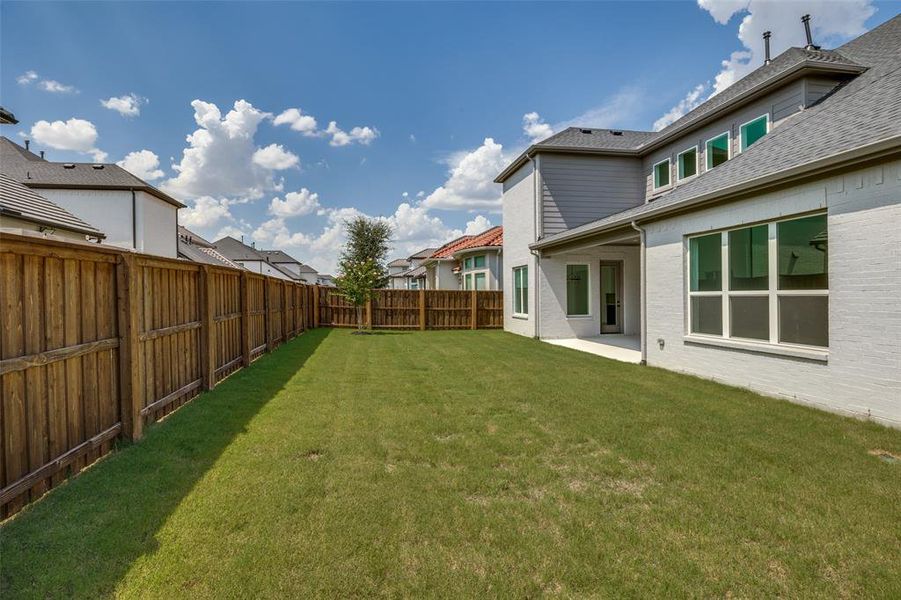Spacious backyard with a large grassy area, privacy fencing, and covered patio Spacious backyard with a large grassy area, privacy fencing, and covered patio