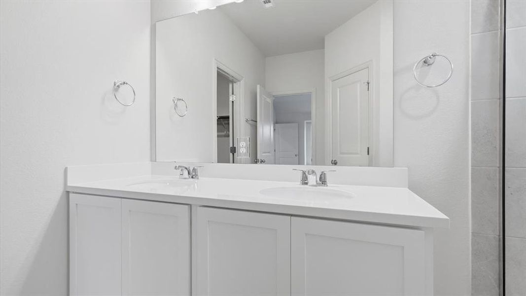 Dual vanity featuring white cabinetry, integrated sinks, chrome faucets, and a large wall-mounted mirror