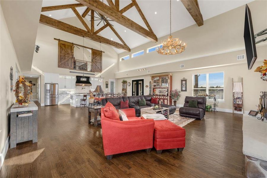 Living room featuring high vaulted ceiling, dark wood finished floors, beamed ceiling, plenty of natural light, and a chandelier