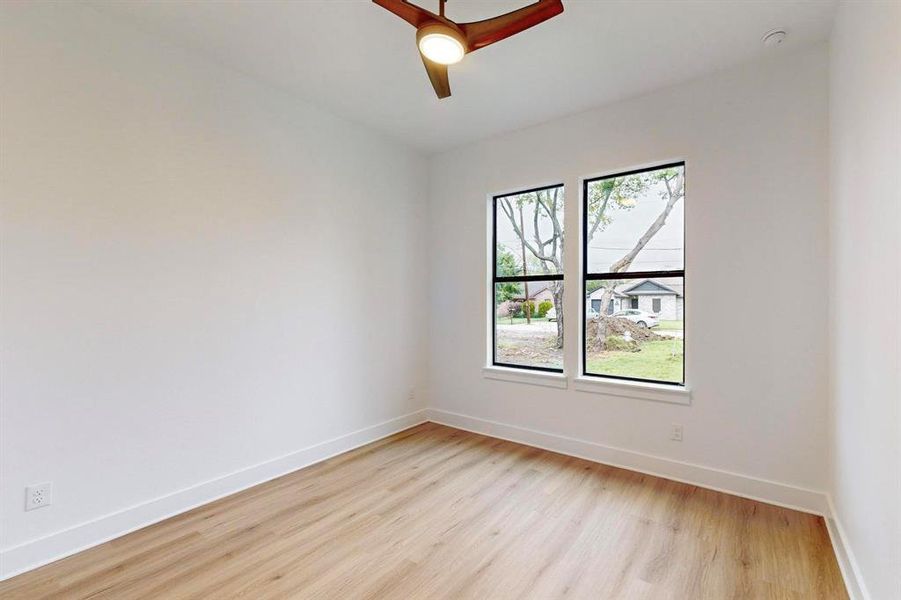Room featuring wood-finish flooring, crisp white walls, and a contemporary ceiling fan with integrated lighting Room featuring wood-finish flooring, crisp white walls, and a contemporary ceiling fan with integrated lighting