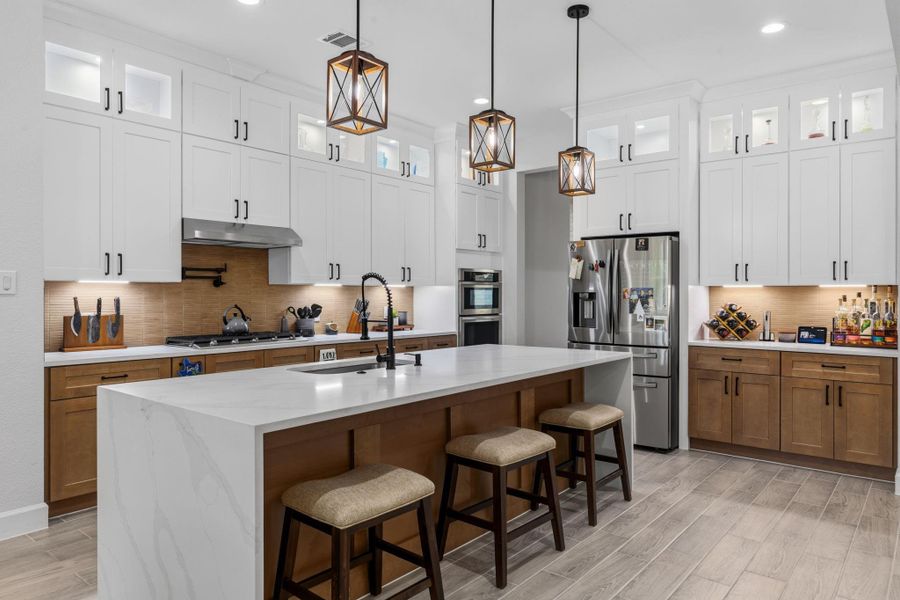 KITCHEN - Statement kitchen features custom cabinetry, waterfall island, pot filler and wine fridge.