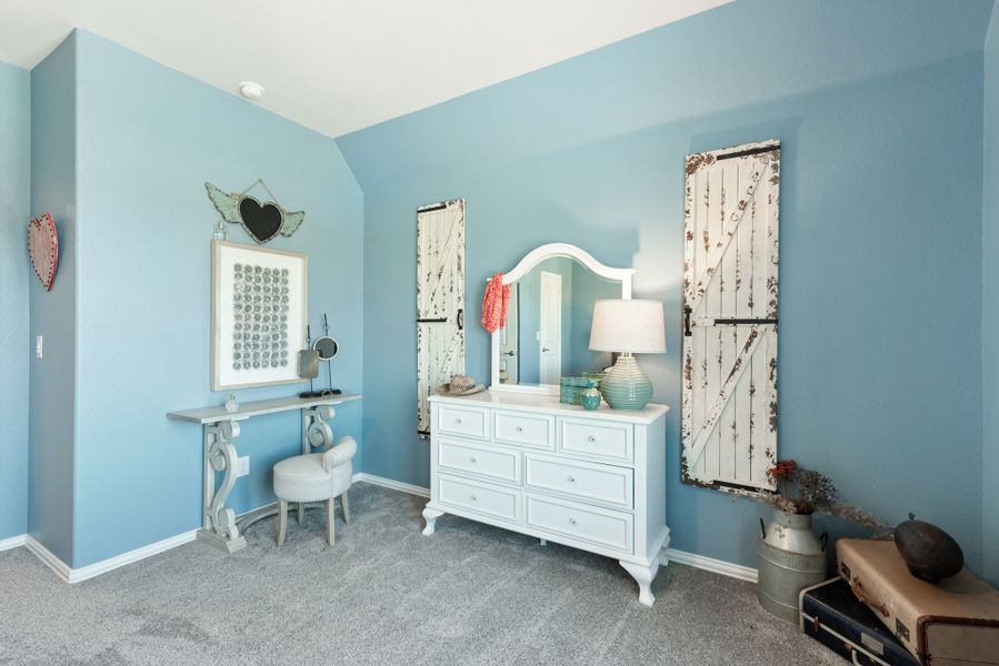 Bedroom with blue walls, white dresser with mirror, vanity table, and rustic door panel decor on carpet floor