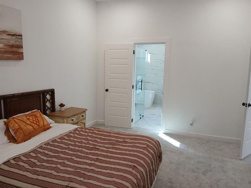 Spacious room featuring light gray carpeting, crisp white walls, and a five-panel interior door