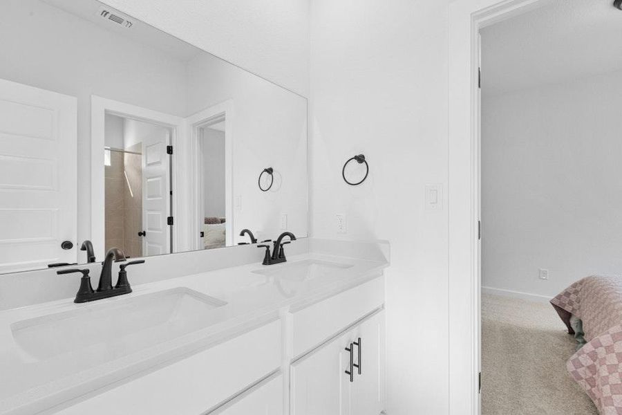 Bathroom featuring light colored carpet, double vanity, and a shower Bathroom featuring light colored carpet, double vanity, and a shower