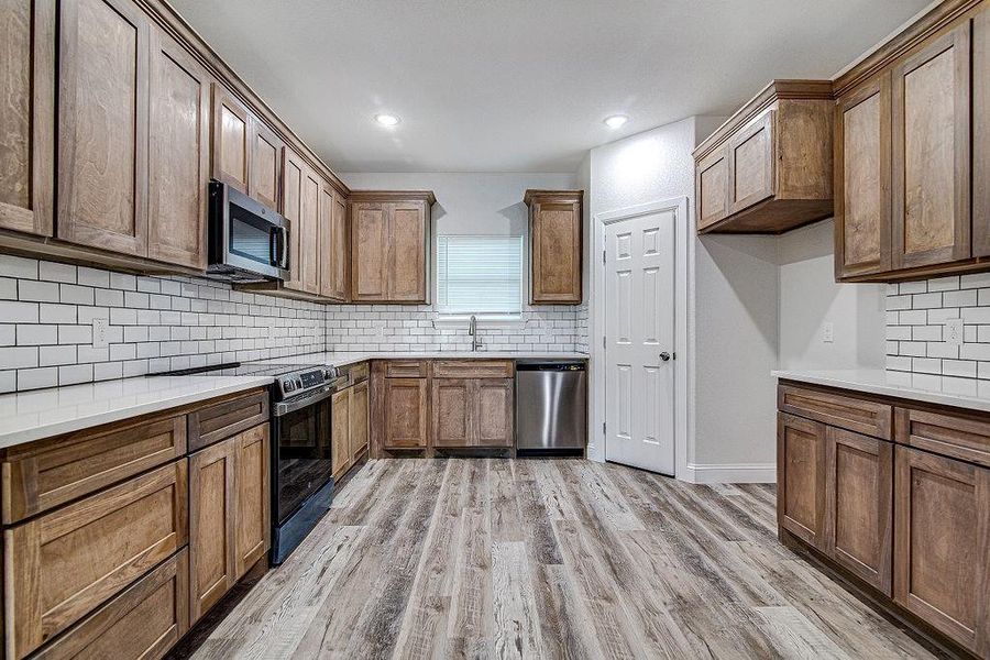 Kitchen featuring stainless steel appliances, backsplash, light hardwood / wood-style flooring, and sink