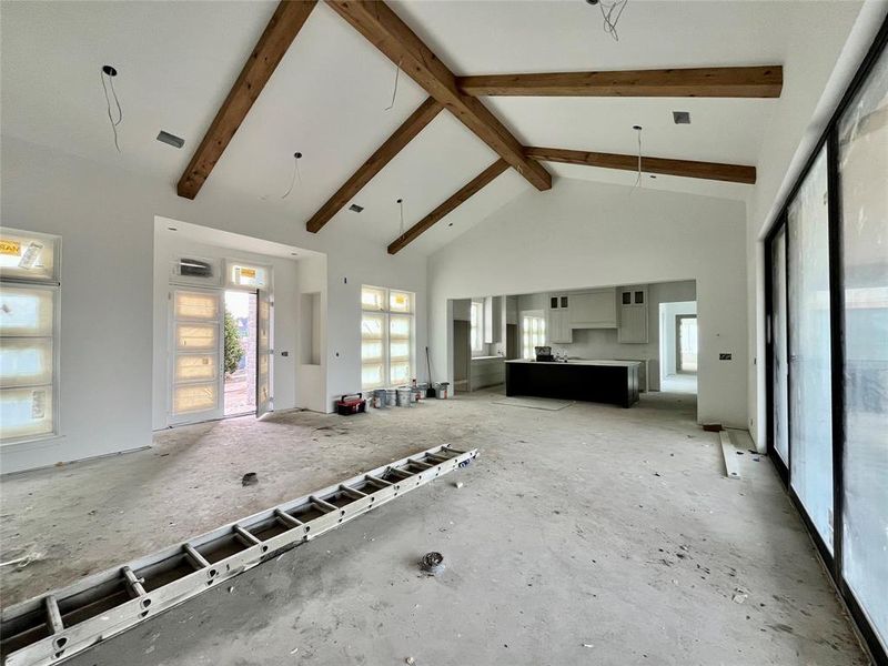 Unfurnished living room with beam ceiling and high vaulted ceiling