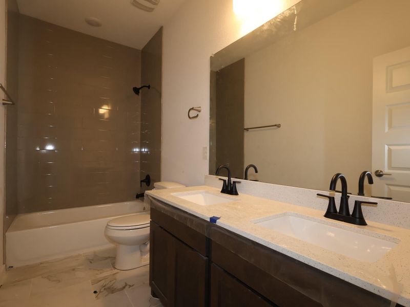 Dual vanities with pristine countertops and sleek dark fixtures elevate this modern bathroom.