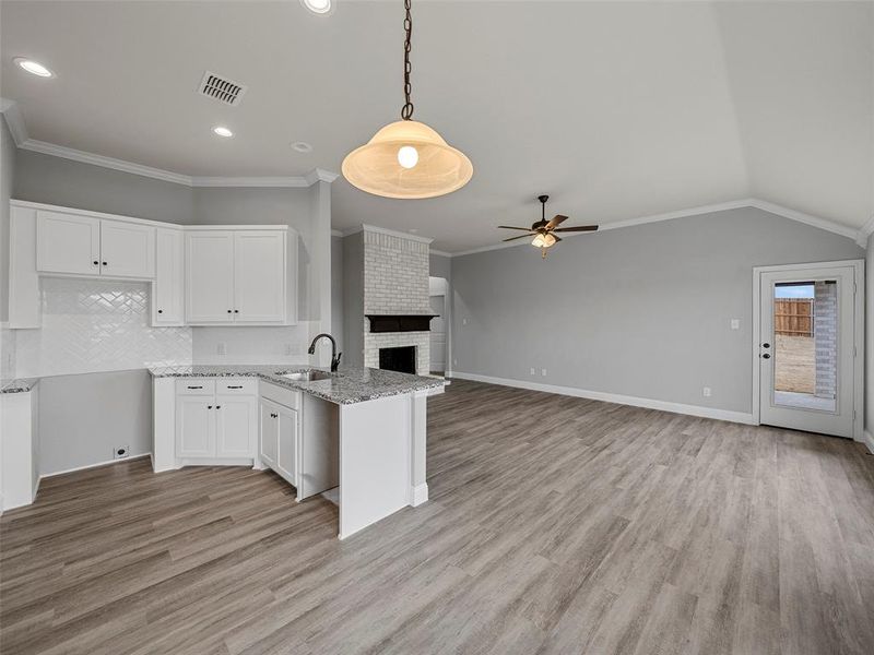 Kitchen with visible vents, a sink, open floor plan, white cabinetry, and a fireplace