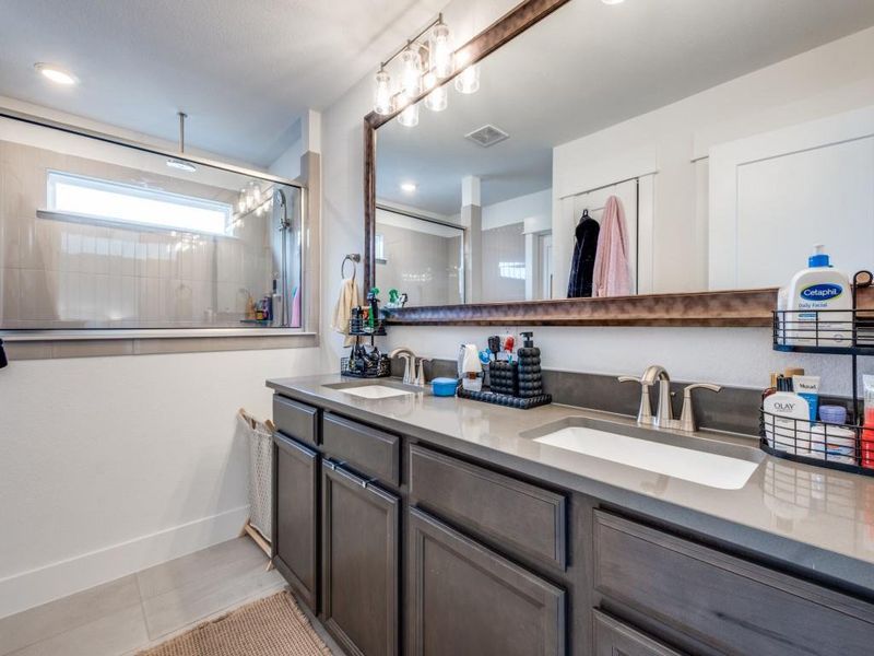 Bathroom featuring double vanity, tile patterned flooring, and walk in shower