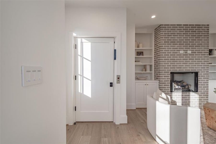 Entrance foyer with light hardwood / wood-style flooring and a brick fireplace