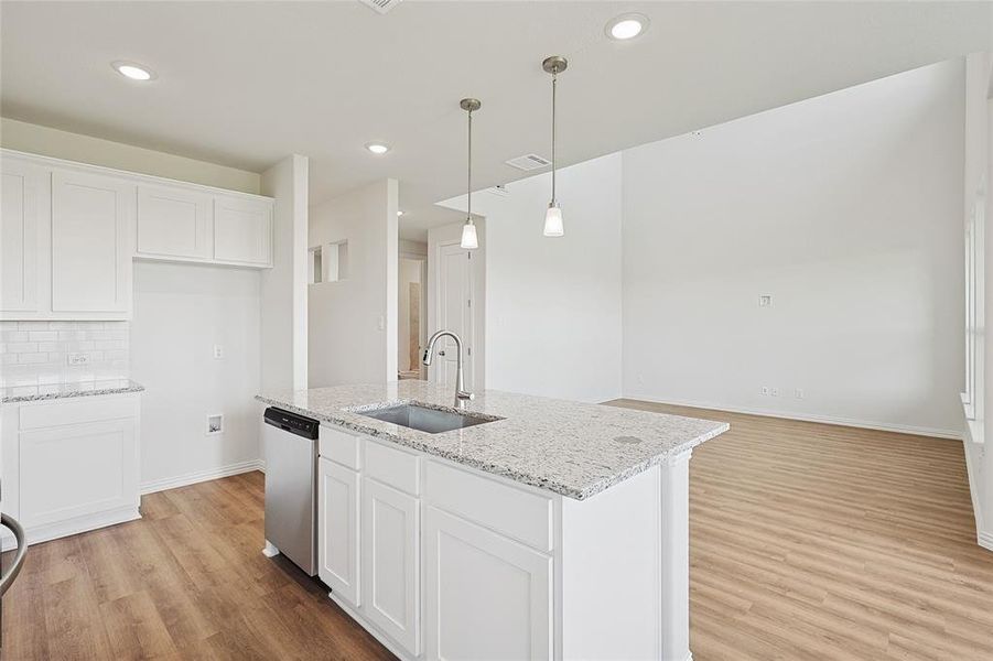 Kitchen with stainless steel dishwasher, white cabinets, and light wood-type flooring