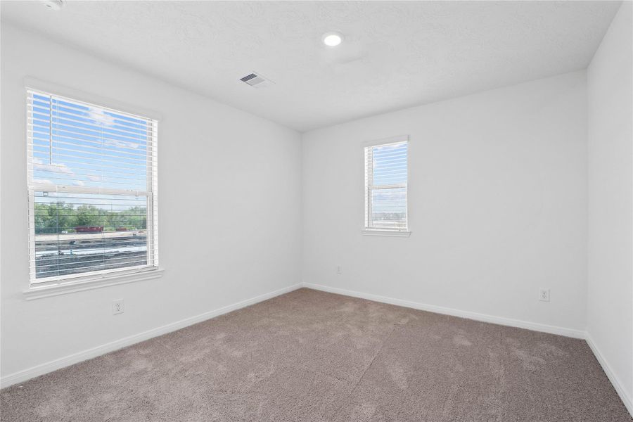 This secondary bedroom offers comfort and style with plush carpeting, neutral paint tones, recessed lighting, large windows with blinds, and a generously sized closet. This secondary bedroom offers comfort and style with plush carpeting, neutral paint tones, recessed lighting, large windows with blinds, and a generously sized closet.