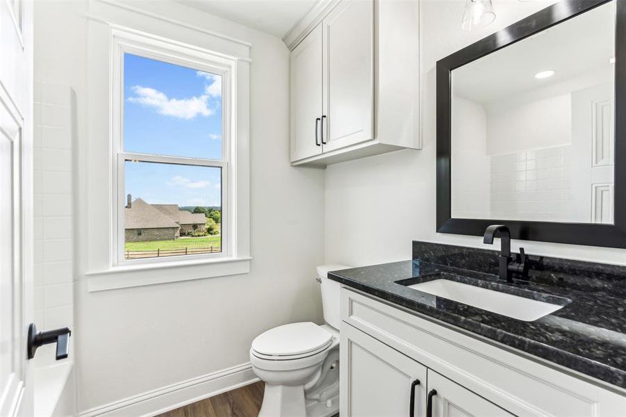 Full upstairs bathroom featuring vanity, toilet, shower over tub, and hardwood / wood-style floors