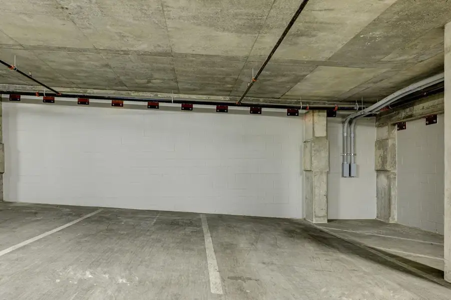 Dedicated parking space within a concrete parking structure, featuring painted block walls and exposed concrete ceiling