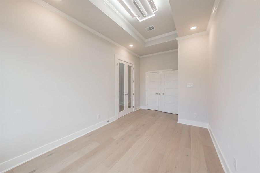 Unfurnished bedroom featuring light wood-style floors, recessed lighting, crown molding, and french doors