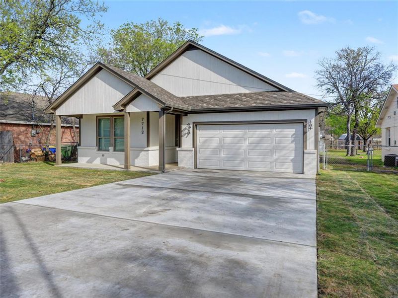 Ranch-style house featuring roof with shingles, an attached garage, driveway, brick siding, and a porch