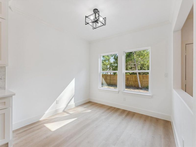 Unfurnished dining area featuring light wood-type flooring, crown molding, and a chandelier