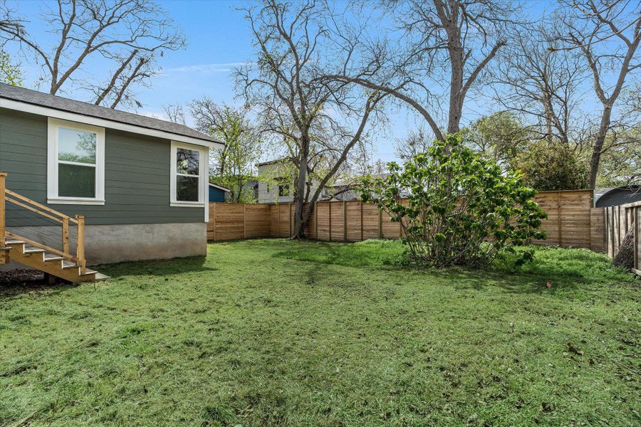 The property features a spacious yard with a lawn, mature trees, and a wooden fence providing privacy The property features a spacious yard with a lawn, mature trees, and a wooden fence providing privacy