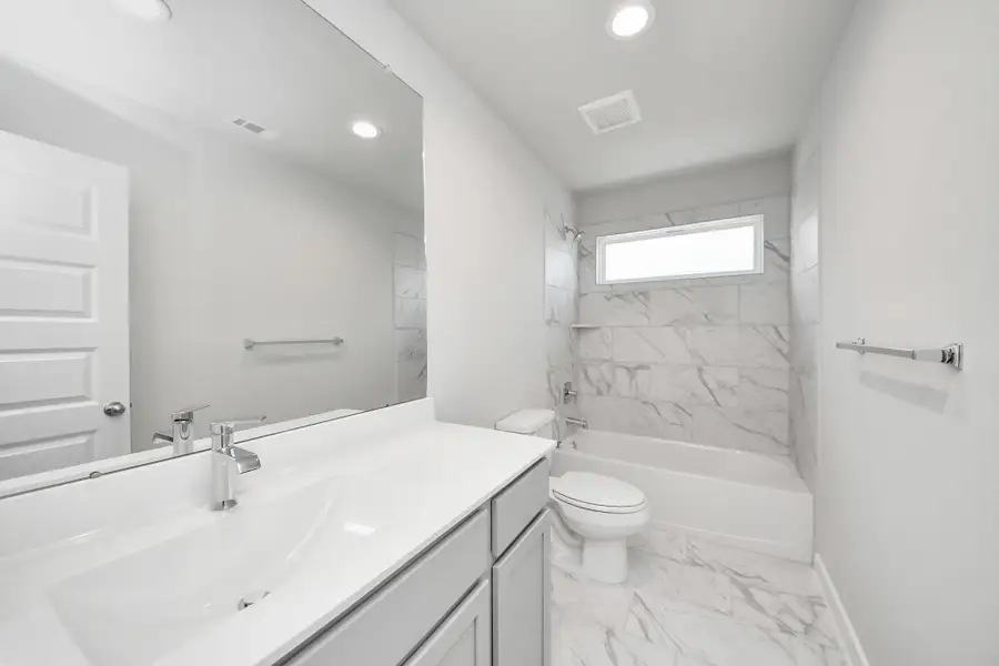Secondary bath features tile flooring, bath/shower combo with tile surround, light stained wood cabinets, beautiful light countertop. Sample photo of completed home with similar floor plan. Actual colors and selections may vary.